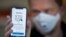 FILE - A man holds a smartphone showing a tracking and tracing app launched by the National Institute of Public Health to try to halt a return of the new coronavirus, in Oslo, Norway, April 17, 2020.