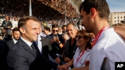 El presidente francés Emmanuel Macron estrecha la mano de los espectadores durante la ceremonia de llegada de la antorcha olímpica en Marsella, sur de Francia, el miércoles 8 de mayo de 2024.