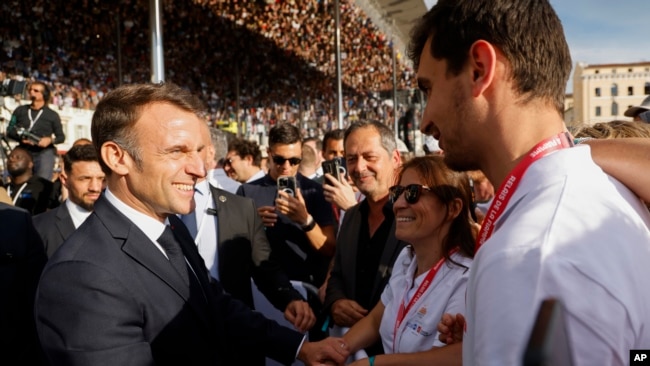 El presidente francés Emmanuel Macron estrecha la mano de los espectadores durante la ceremonia de llegada de la antorcha olímpica en Marsella, sur de Francia, el miércoles 8 de mayo de 2024.