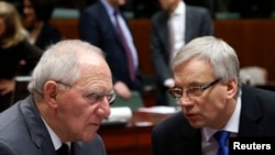 Germany's Finance Minister Wolfgang Schaeuble listens to his Lithuanian counterpart Rimantas Sadzius (R) during a European Union finance ministers meeting in Brussels, Dec. 10, 2013.