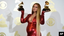 Beyonce poses in the press room with the awards for best music video for "Formation" and best urban contemporary album for "Lemonade" at the 59th annual Grammy Awards at the Staples Center, Feb. 12, 2017, in Los Angeles.