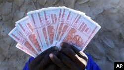 A man holds a handful of 5 Billion Zimbabwean dollar notes, in Harare.