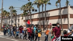 Familias compuestas por inmigrantes solicitantes de asilo se dirigen hacia un refugio temporal en McAllen, Texas, EE. UU. en abril de 2021.