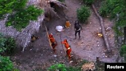 Members of an uncontacted Amazon Basin tribe and their dwellings are seen during a flight over the Brazilian state of Acre along the border with Peru in May, 2008.
