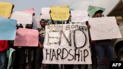 Demonstrators hold placards during a protest against price hikes and economic hardships in Ibadan on February 19, 2024. 