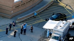 FILE - Officials stand outside of Sandy Hook Elementary School in Newtown, Conn., where authorities gunman Adam Lanza opened fire inside the school killing 20 first-graders and six educators at the school, and killed himself as police arrived, Dec. 14, 20