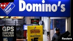 Seorang pekerja sedang mengantar pizza dari sebuah gerai Domino's di Sydney,Australia. (Foto:dok/Reuters)