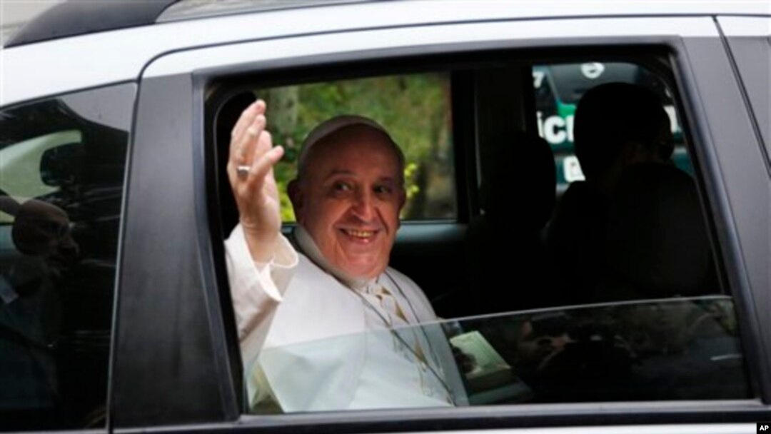 Paus Fransiskus melambaikan tangannya ke arah para wartawan, dari mobil yang membawanya menuju Basilika Aparecida di Rio de Janeiro, Brazil (24/7).