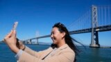 Content creator Cynthia Huang Wang works below the San Francisco-Oakland Bay Bridge in San Francisco, Monday, April 8, 2024. (AP Photo/Eric Risberg)