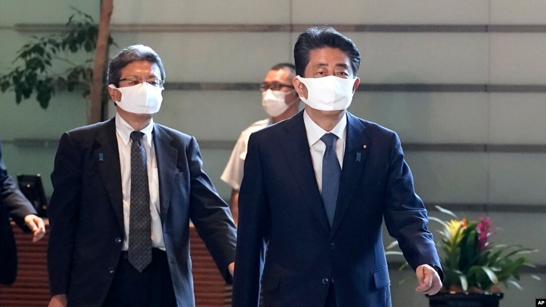 Perdana Menteri Jepang Shinzo Abe, kanan, berjalan di kantor perdana menteri di Tokyo Jumat, 28 Agustus 2020. Perdana menteri terlama Jepang Abe bermaksud meninggalkan jabatannya karena kesehatan yang menurun, menurut partai politiknya. (Foto: AP)