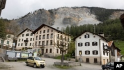 FILE - Residential buildings stand in front of the "Brienzer Rutsch" the rockfall danger zone in Brienz, Switzerland, on May 12, 2023.