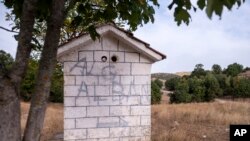 Tanda darurat di kapel Ortodoks Yunani menunjukkan jalan ke Albania, dekat desa Ieropigi, Yunani utara, di perbatasan Yunani-Albania, 28 September 2021. (AP Photo/Giannis Papanikos)