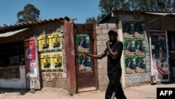 A man walks past election campaign posters for candidates in the Mabvuku-Tafara constituency on December 9, 2023. 