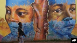 FILE - A woman walks past an informational mural against gender based violence, on a street in Nairobi, Kenya, March 6, 2024.