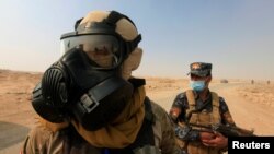 Iraqi forces wear protective masks after winds brought fumes from a nearby sulfur plant set aafire by IS militants, in Qayyara, Iraq, Oct. 22, 2016. Fears are mounting that the jihadist group, in its fight for Mosul, would not hesitate to use chemical weapons.