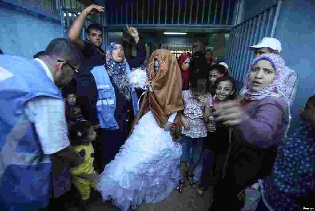 People gather around a homeless Palestinian bride during her wedding ceremony at a United Nations-run school sheltering displaced Palestinians, in Rafah in the southern Gaza, Strip Aug. 17, 2014.