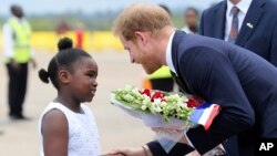 Britain's Prince Harry receives flowers from a girl upon his arrival at Kenneth Kaunda airport in Lusaka, Nov. 26, 2018. 