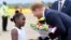 Britain's Prince Harry receives flowers from a girl upon his arrival at Kenneth Kaunda airport in Lusaka, Nov. 26, 2018. 