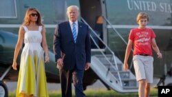 FILE - President Donald Trump, first lady Melania Trump and son Barron Trump walk across the tarmac to board Air Force One at Morristown Municipal Airport, Aug. 20, 2017, in Morristown, N.J.