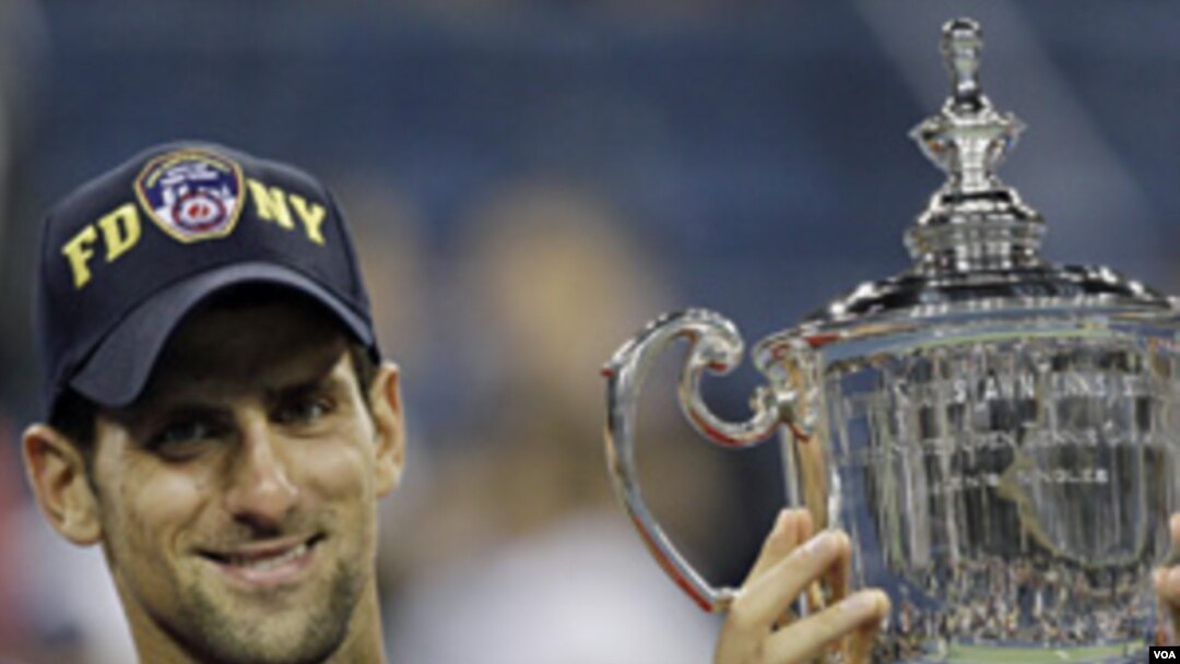 Novak Djokovic memegang trophy setelah menang melawan Rafael Nadal di turnamen grandslam AS Terbuka di New York (12/9).