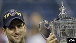 Novak Djokovic memegang trophy setelah menang melawan Rafael Nadal di turnamen grandslam AS Terbuka di New York (12/9).