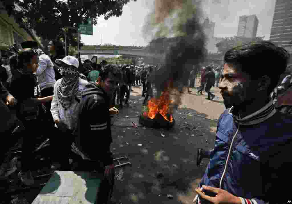 Massa membakar ban saat bentrok dengan aparat polisi di Jakarta, Rabu, 22 Mei 2019. (Foto: AP/Dita Alangkara)