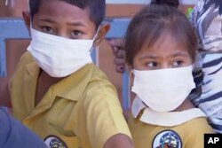 FILE - Children, their faces covered with masks, wait to get vaccinated against measles at a health clinic in Apia, Samoa, Nov. 18, 2019.