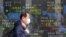 A man walks by an electronic stock board of a securities firm in Tokyo, Wednesday, Jan. 20, 2021. Asian shares were mostly higher Wednesday, ahead of Joe Biden's inauguration as president, ending President Donald Trump’s four-year term. Japan's…