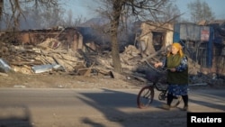 Una residente local camina con una bicicleta, en el lugar de los ataques aéreos rusos, en medio del ataque de Rusia a Ucrania, en la aldea de Lyptsi, región de Járkov, Ucrania, el 10 de abril de 2024.