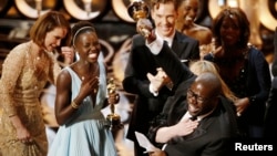 El director y productor Steve McQueen (derecha) celebra el Oscar a mejor película por "12 años como esclavo", junto a Lupita Nyong'o (izquierda).