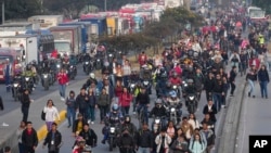 La gente camina por una calle bloqueada por camioneros que protestan por un aumento en los precios del diésel en Bogotá, Colombia, el miércoles 4 de septiembre de 2024.