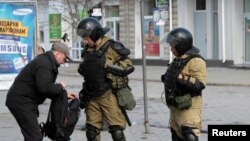 Members of a Crimean self-defense unit spot check a man's bag a street in Simferopol, Crimea, Ukraine, March 17, 2014. 