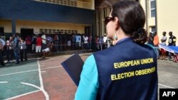 Un observateur de l'Union européenne regardent les citoyens faire la queue pour aller voter à Monrovia, le 10 octobre 2017.