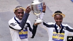 Benson Kipruto, left, and Diana Kipyogei, right, both of Kenya, celebrate at the finish line after winning the men's and women's division of the Boston Marathon in Boston, Oct. 11, 2021.