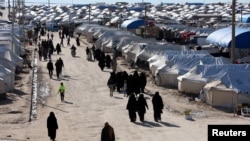 FILE - Women walk through al-Hol displacement camp in Hasaka governorate, Syria, April 1, 2019. 