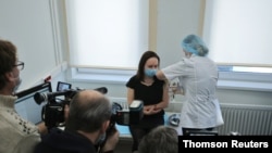 Journalists film as a woman gets injected with Sputnik-V vaccine against the coronavirus disease at a clinic in Moscow, Russia, Dec. 5, 2020.