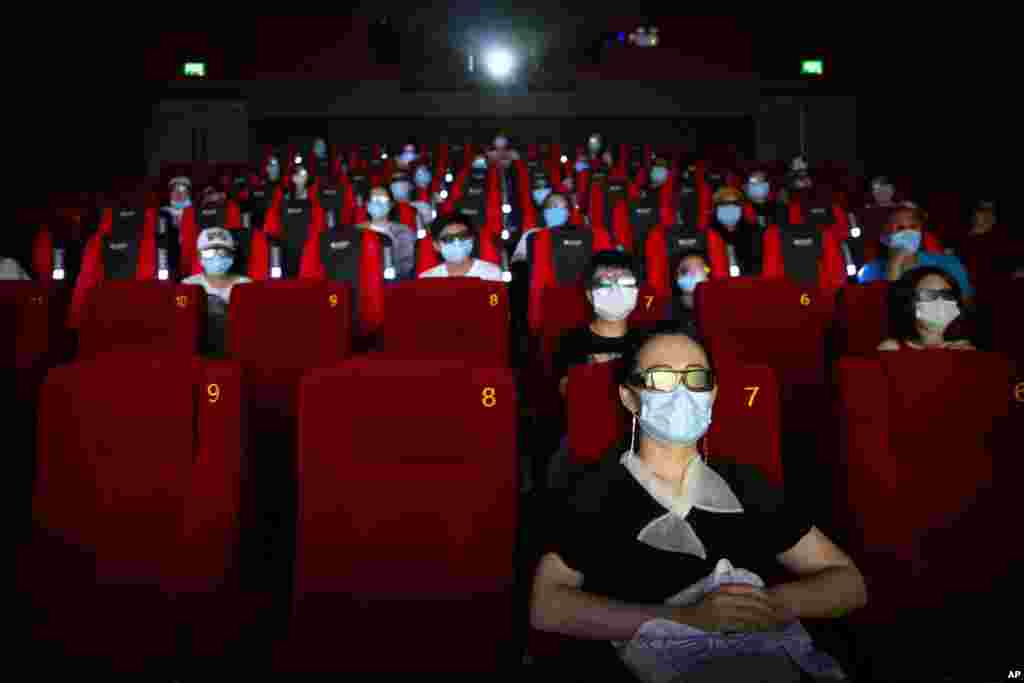 People wearing face masks to protect against the coronavirus sit spaced apart as they watch the film &quot;Dolittle&quot; at a movie theater in Beijing.