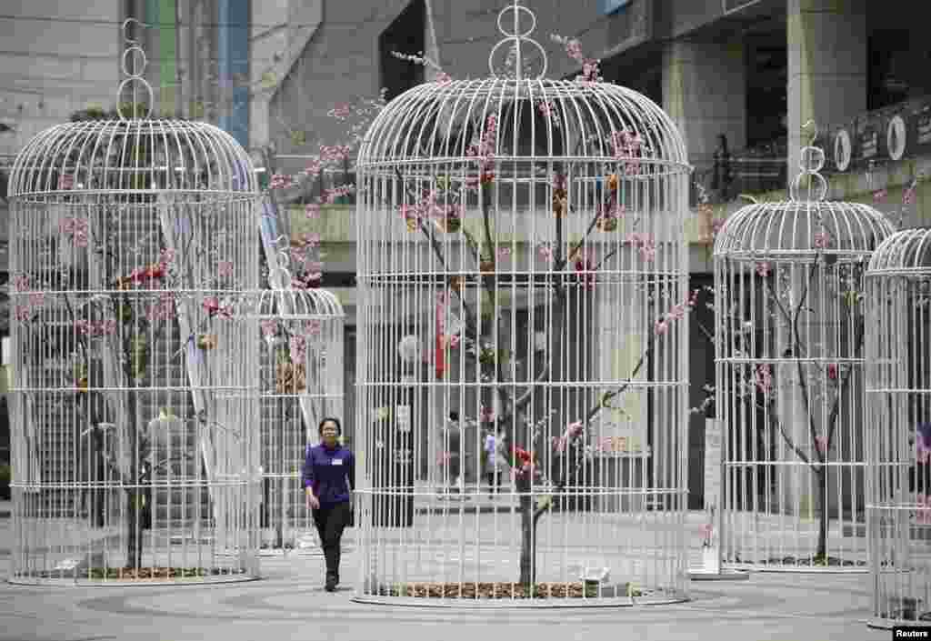 A woman walks past an installation of giant bird cages containing artificial trees and birds on a square in Nanjing, Jiangsu province, China. 