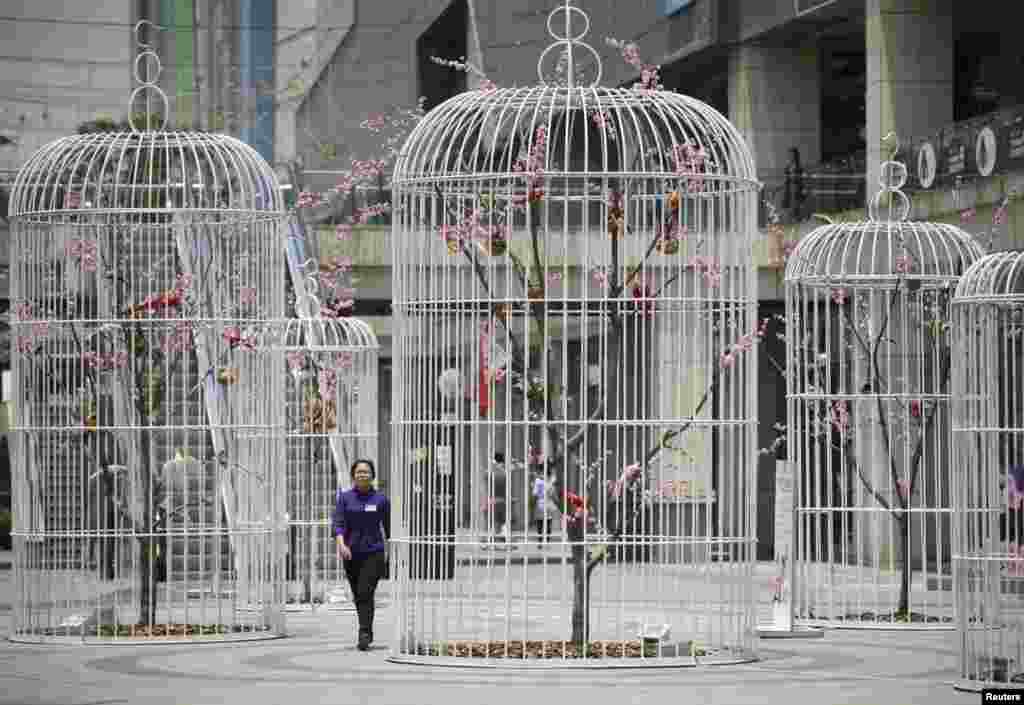 Seorang perempuan berjalan melewati sebuah karya seni &#39;kandang burung raksasa&#39; yang berisi pohon-pohon buatan dan burung di kota Nanjing, provinsi Jiangsu, China.