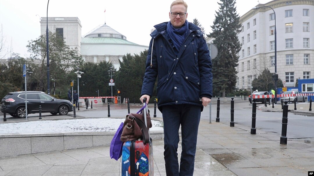 Polish lawmaker Michal Stasinski poses in front of the parliament pulling a suitcase with warm clothes and carrying a bag filled with his mother's homemade cabbage-and-mushroom stuffed dumplings in Warsaw, Poland, Dec. 23, 2016. Stasinski was joining a group of opposition lawmakers hunkering down for sit-in occupation of parliament to protest what they consider backsliding on democracy by the populist government. 