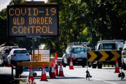 A COVID-19 signage is seen at a vehicle checkpoint on the Pacific Highway on the Queensland - New South Wales border in Brisbane on April 15, 2020.