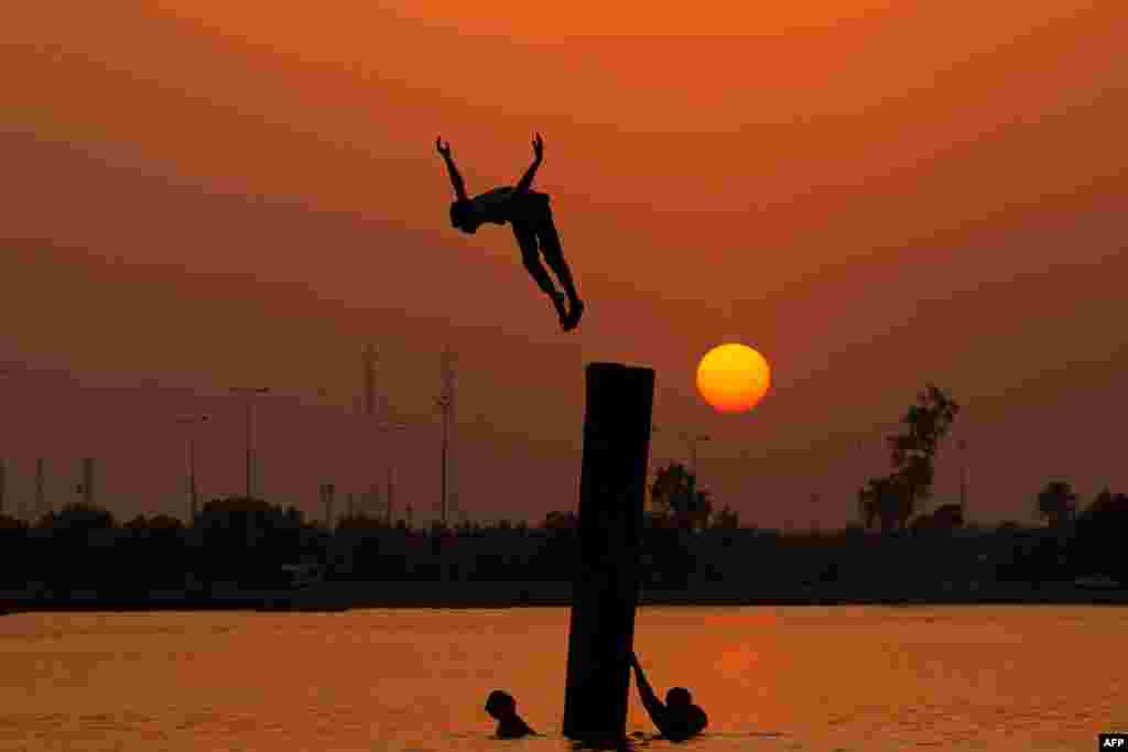 An Iraqi youth swims in the Shatt Al-Arab River by the port of Maqil, amid a heat wave in the southern city of Basra, June 29, 2021.