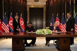 FILE U.S. President Donald Trump and North Korea's leader Kim Jong Un sign documents that acknowledge the progress of the talks and pledge to keep momentum going, after their summit at the Capella Hotel on Sentosa island in Singapore, June 12, 2018.