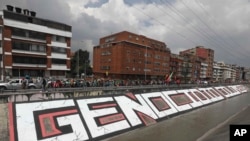 ARCHIVO - Indígenas marchan junto a la palabra española "Genocidio" para protestar contra el gobierno en Bogotá, Colombia, el lunes 19 de octubre de 2020.