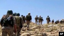 FILE - This frame grab from video released July 22, 2017, and provided by the government-controlled Syrian Central Military Media, shows Hezbollah fighters advancing up a hill in an area on the Lebanon-Syria border.