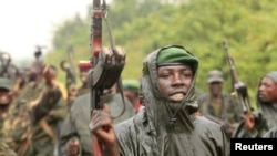 M23 rebel fighters celebrate in the rain at Rumangabo after government troops abandoned the town 23 kilometers north of the eastern Congolese city of Goma, July 28, 2012.