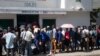 Un grupo de haitianos hacen una fila frente a una oficina de inmigración mientras esperan su turno para solicitar un pasaporte, el martes 10 de enero de 2023, en Puerto Príncipe, Haití. (AP Foto/Odelyn Joseph)