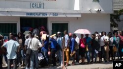 Un grupo de haitianos hacen una fila frente a una oficina de inmigración mientras esperan su turno para solicitar un pasaporte, el martes 10 de enero de 2023, en Puerto Príncipe, Haití. (AP Foto/Odelyn Joseph)