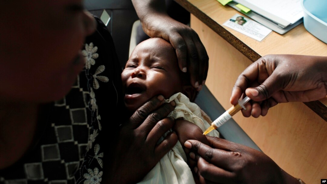 FILE - A mother holds her baby receiving a new malaria vaccine as part of a trial at the Walter Reed Project Research Center in Kombewa in Western Kenya. 