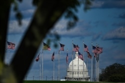 FILE - The dome of the U.S. Capitol building is seen behind a row of U.S. flags in Washington, April 10, 2020.